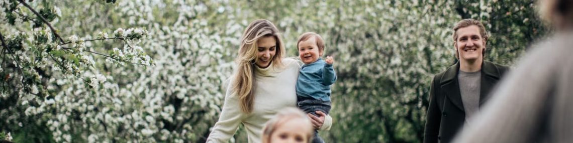 A joyful family enjoys a playful day outdoors amidst blossoming trees in spring.